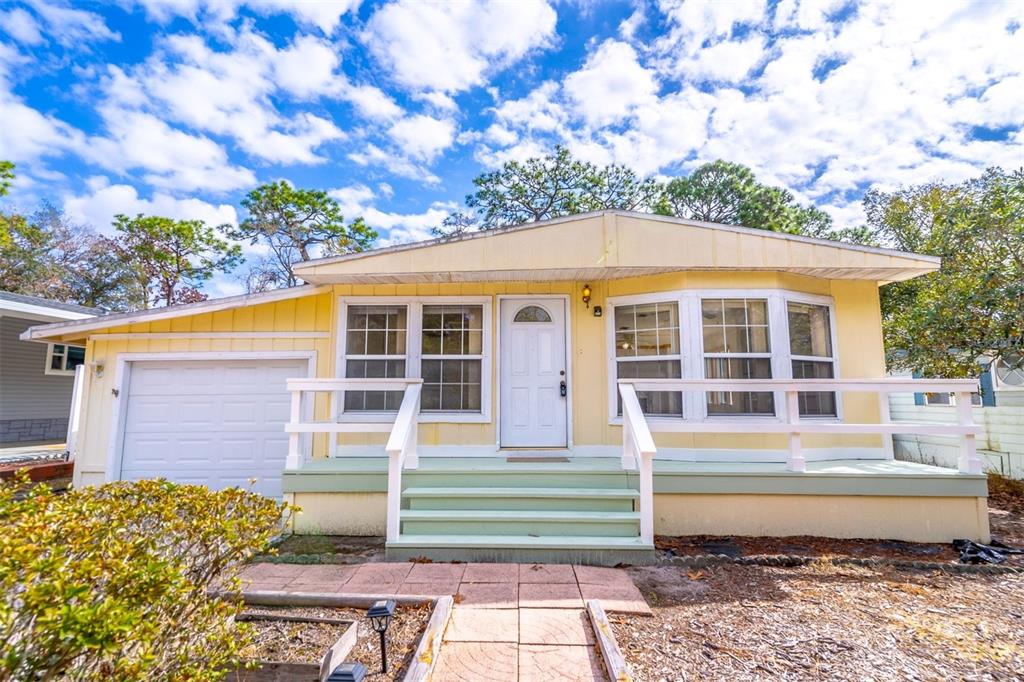 A yellow single-story house with a white front door, porch, and attached garage — 320 N FOREST BOULEVARD, LAKE MARY, FL