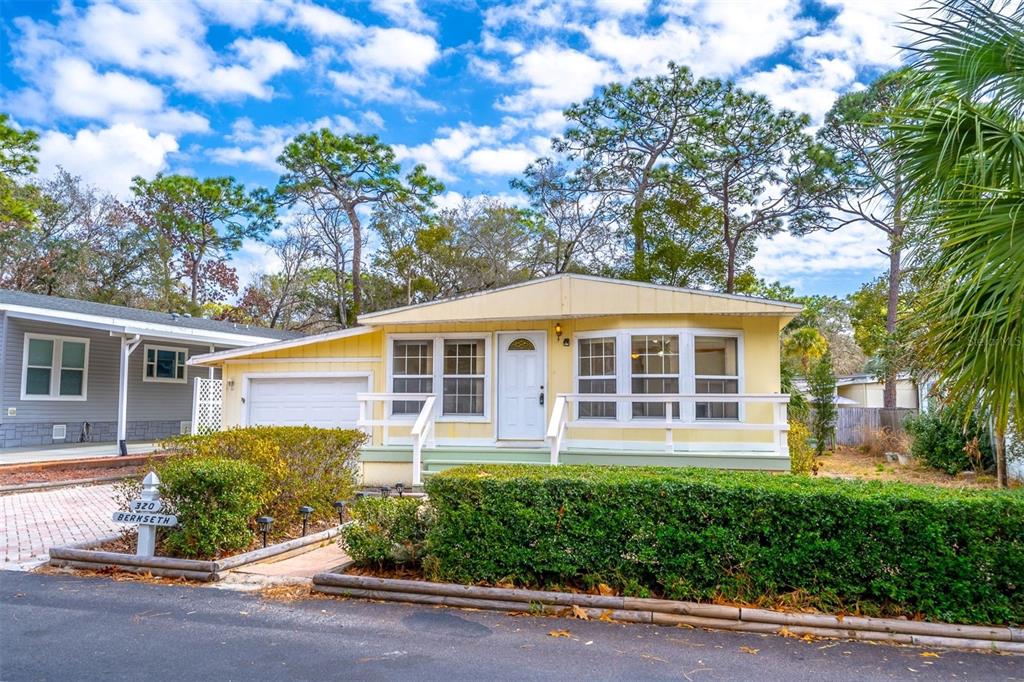 A yellow single-story house with a white front door and a manicured hedge — 320 N FOREST BOULEVARD, LAKE MARY, FL