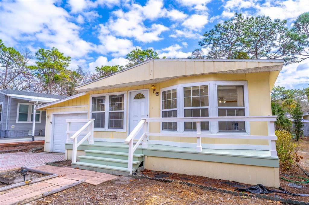 A yellow mobile home with a white front door, a porch, and a small garage — 320 N FOREST BOULEVARD, LAKE MARY, FL