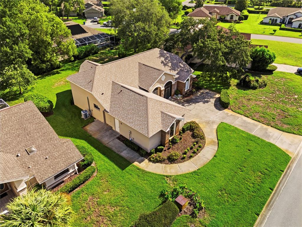 An aerial view shows a tan house with a shingled roof, driveway, and landscaped yard — 9415 ASHLEY DRIVE, WEEKI WACHEE, FL