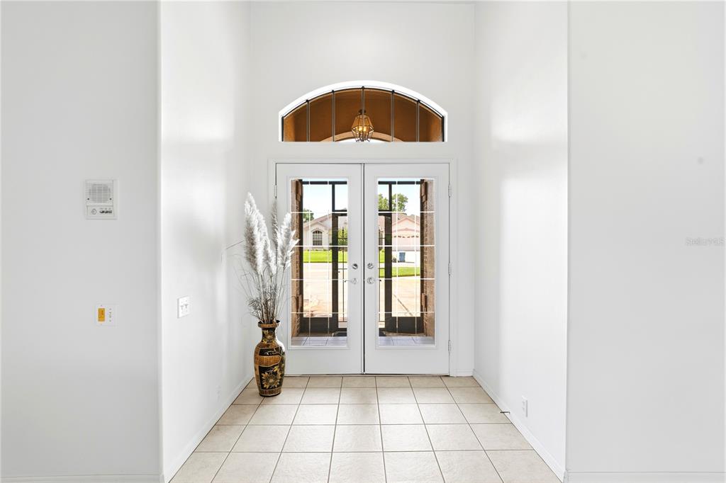 A bright entryway features white walls, tiled flooring, and double glass doors with an arched transom — 9415 ASHLEY DRIVE, WEEKI WACHEE, FL