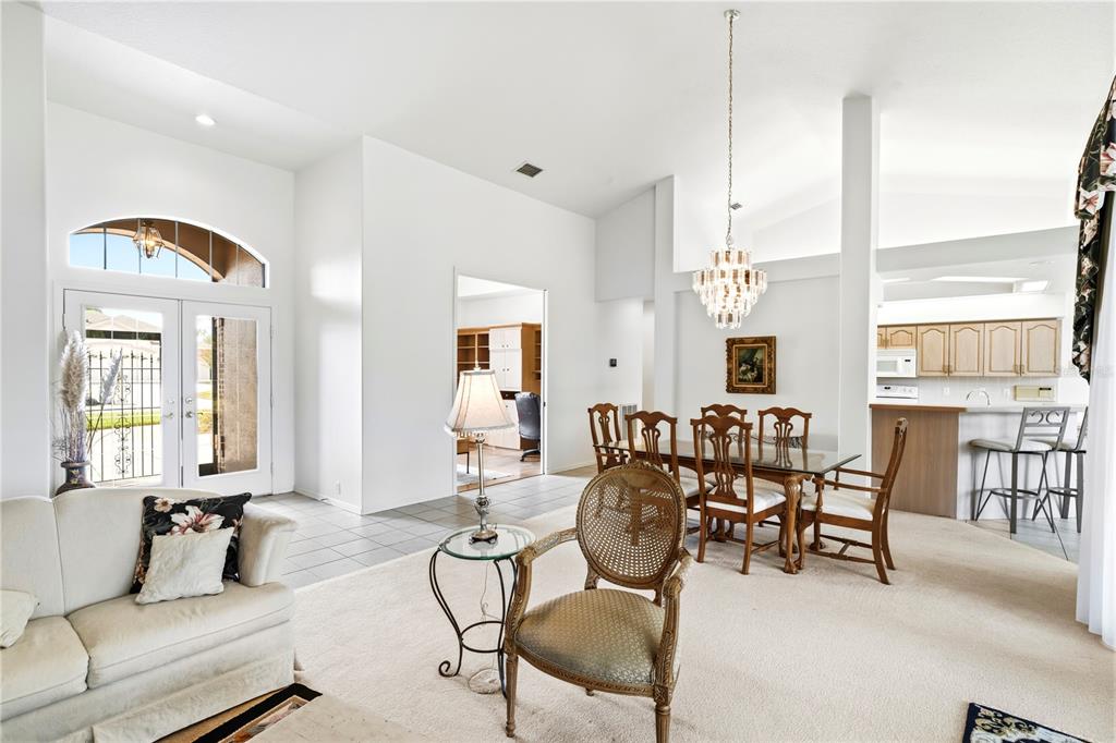 A living and dining area with white walls, carpeted floors, and a crystal chandelier — 9415 ASHLEY DRIVE, WEEKI WACHEE, FL