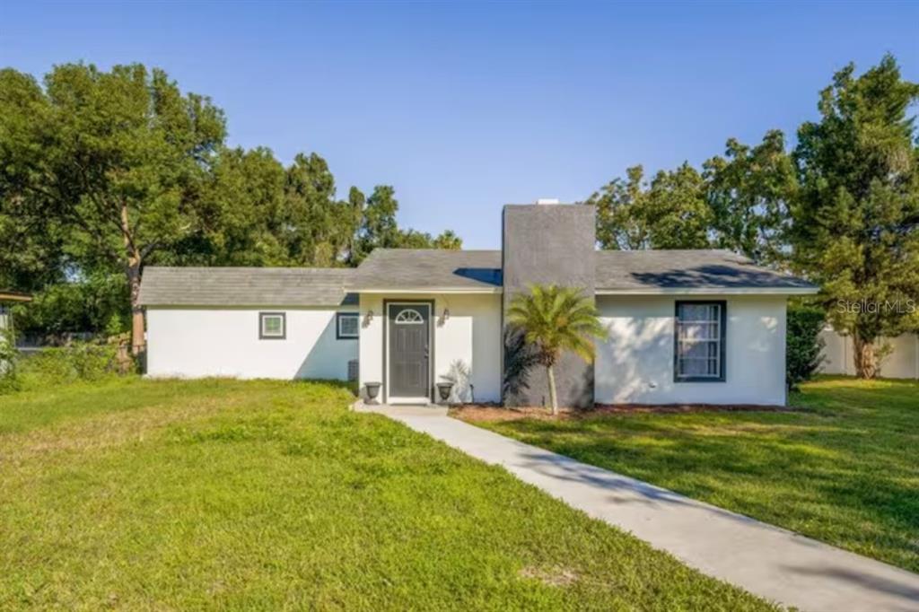 A single-story house with white stucco walls, a dark front door, and a grey chimney — 2301 CARLTON DRIVE UNIT 3, ORLANDO, FL