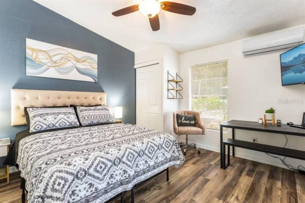 A bedroom features a patterned bed, a dark accent wall, a desk, and wood-look flooring — 2301 CARLTON DRIVE UNIT 3, ORLANDO, FL