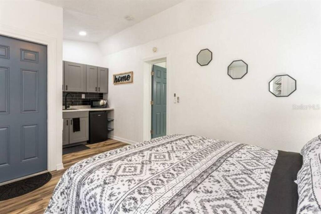 A bedroom features a kitchenette with gray cabinets, a bed, and three hexagonal wall mirrors — 2301 CARLTON DRIVE UNIT 3, ORLANDO, FL