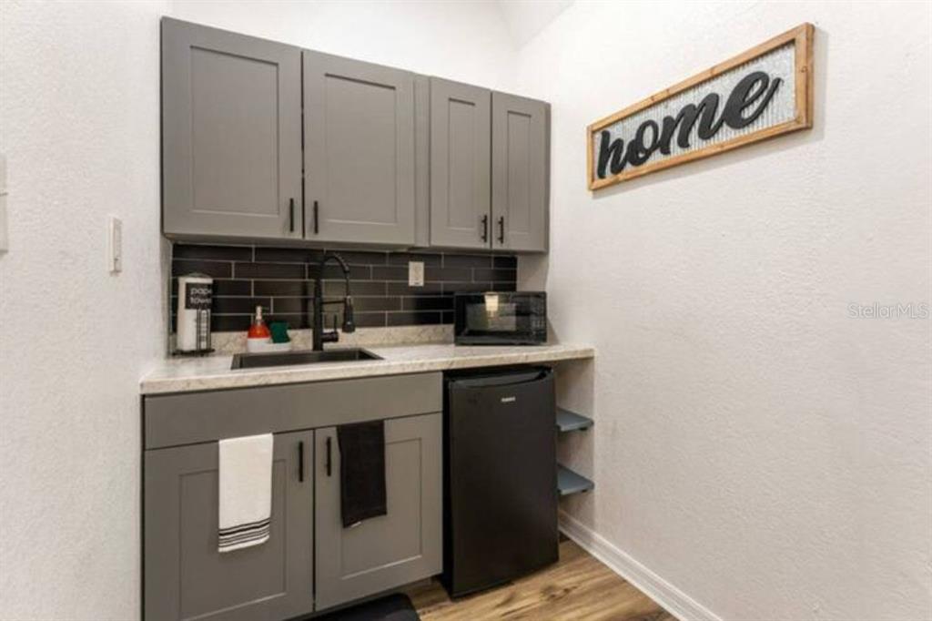 A kitchenette features gray cabinets, a black sink, a mini-fridge, and a black tile backsplash — 2301 CARLTON DRIVE UNIT 3, ORLANDO, FL