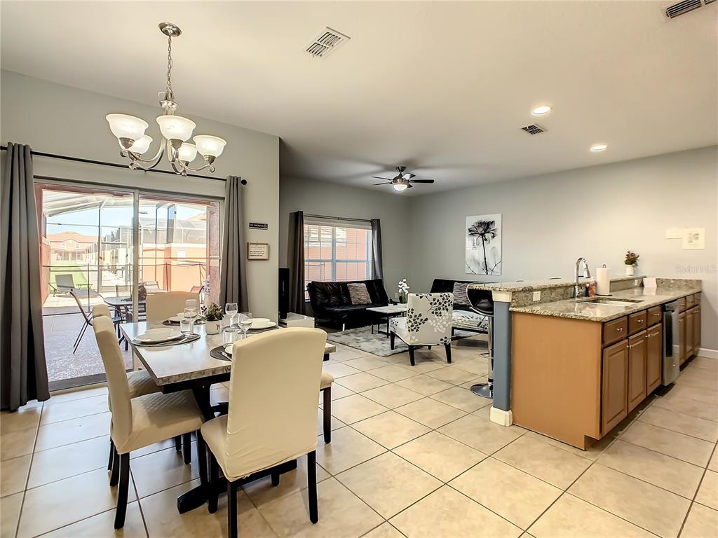 An open-concept dining area and living room with tile floors and a kitchen island — 8845 CANDY PALM ROAD, KISSIMMEE, FL