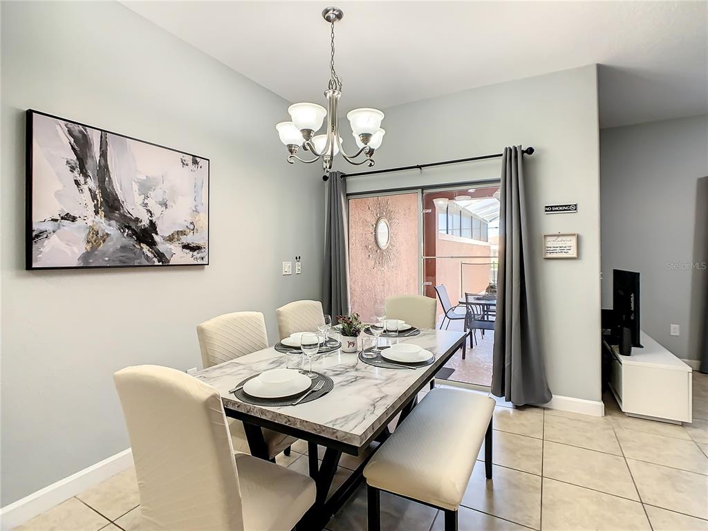 A dining room features a marble-topped table, upholstered chairs, a chandelier, and sliding glass doors — 8845 CANDY PALM ROAD, KISSIMMEE, FL