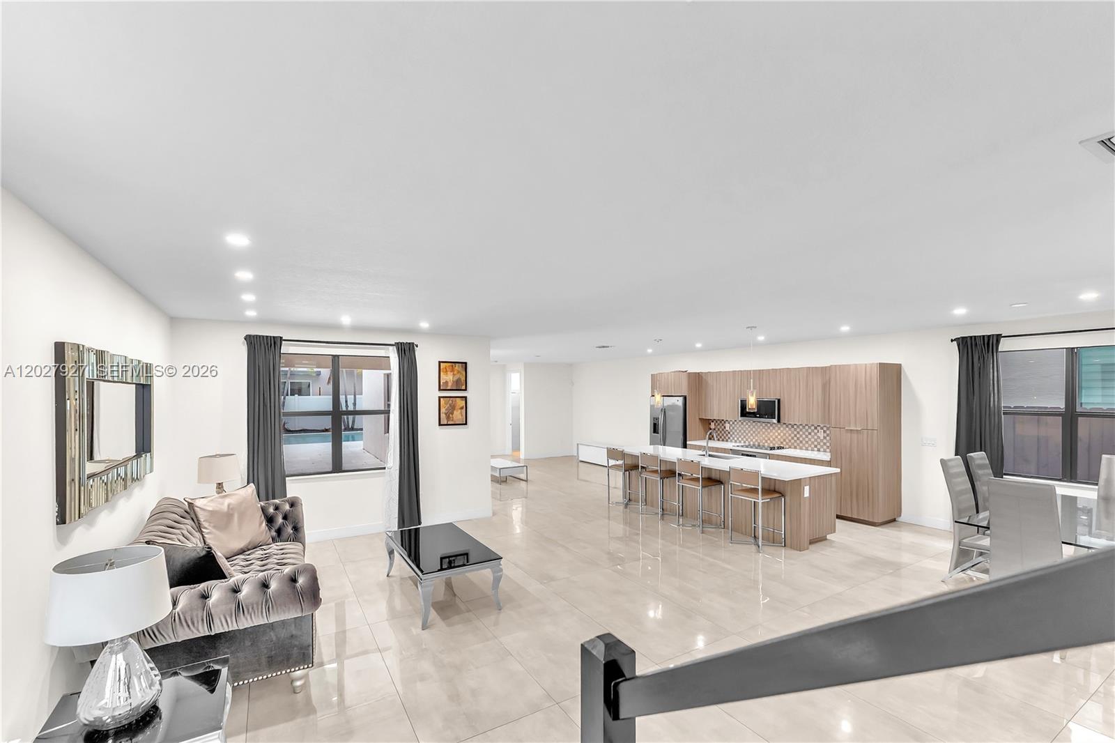 A modern open-concept living area features a kitchen with light wood cabinets and tile floors — 10250 NW 76th Ter, Doral FL 33178, DORAL, FL