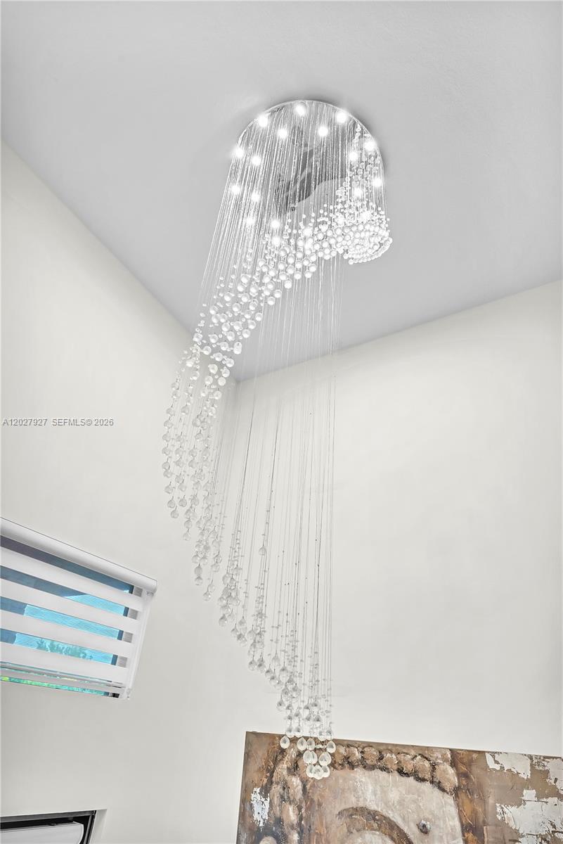 A modern crystal chandelier hangs from a high ceiling above a piece of wall art — 10250 NW 76th Ter, Doral FL 33178, DORAL, FL