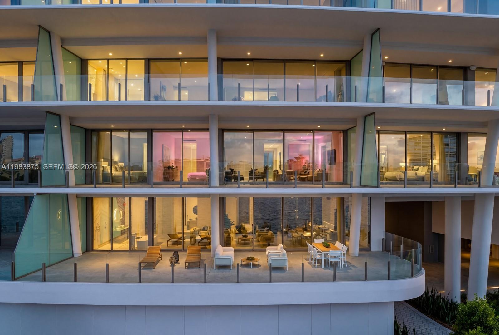 A multi-story building exterior features glass balconies, floor-to-ceiling windows, and outdoor patio furniture — 5 Grove Isle Dr # L205, Miami FL 33133, MIAMI, FL
