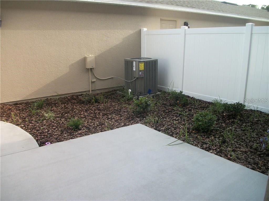 An outdoor patio area features a concrete slab, mulch landscaping, and an air conditioning unit — 12355 LANGSTAFF DRIVE, WINDERMERE, FL