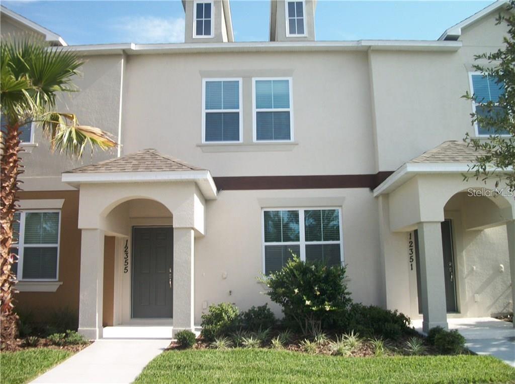 A two-story townhouse exterior features beige stucco walls, dark gray doors, and arched entryways — 12355 LANGSTAFF DRIVE, WINDERMERE, FL