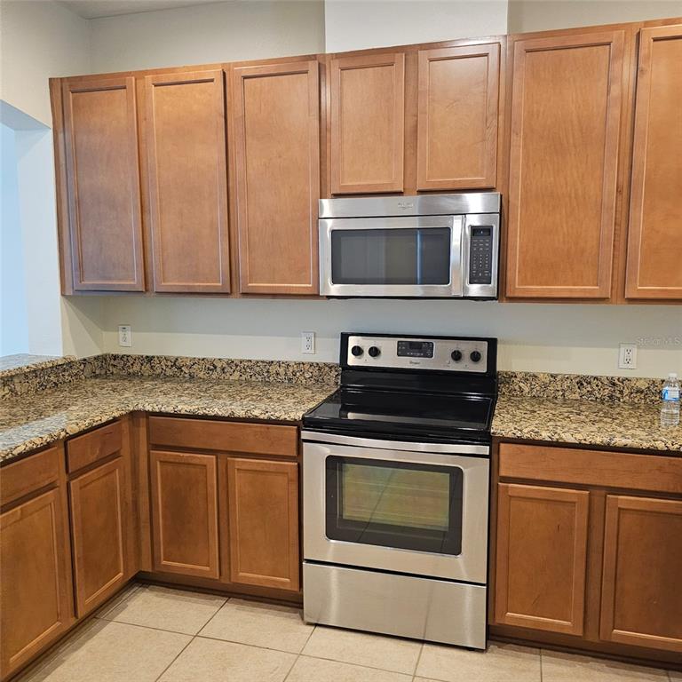 A kitchen features wood cabinets, granite countertops, and stainless steel appliances — 12355 LANGSTAFF DRIVE, WINDERMERE, FL