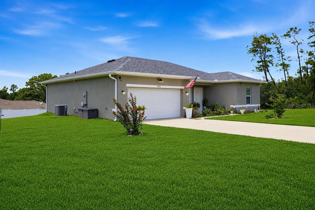 A single-story house with a gray stucco exterior, a two-car garage, and a green lawn — 15943 SW 53RD COURT, OCALA, FL