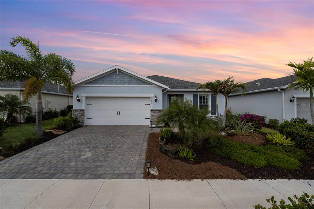 A single-story house with a paved driveway, two-car garage, and landscaped front yard at sunset — 15877 SHORELINE DRIVE, PUNTA GORDA, FL