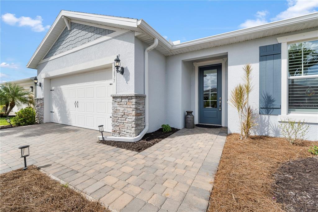 A single-story house exterior features a stone-accented garage, a paved walkway, and a blue door — 15877 SHORELINE DRIVE, PUNTA GORDA, FL