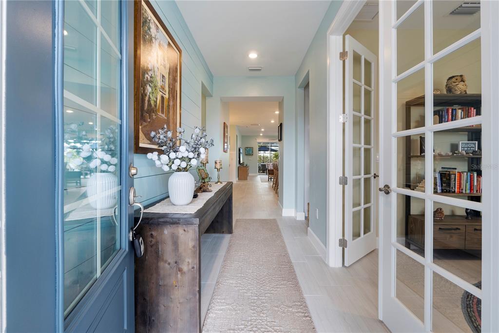 A bright entryway features a rustic console table, light blue walls, and French doors — 15877 SHORELINE DRIVE, PUNTA GORDA, FL