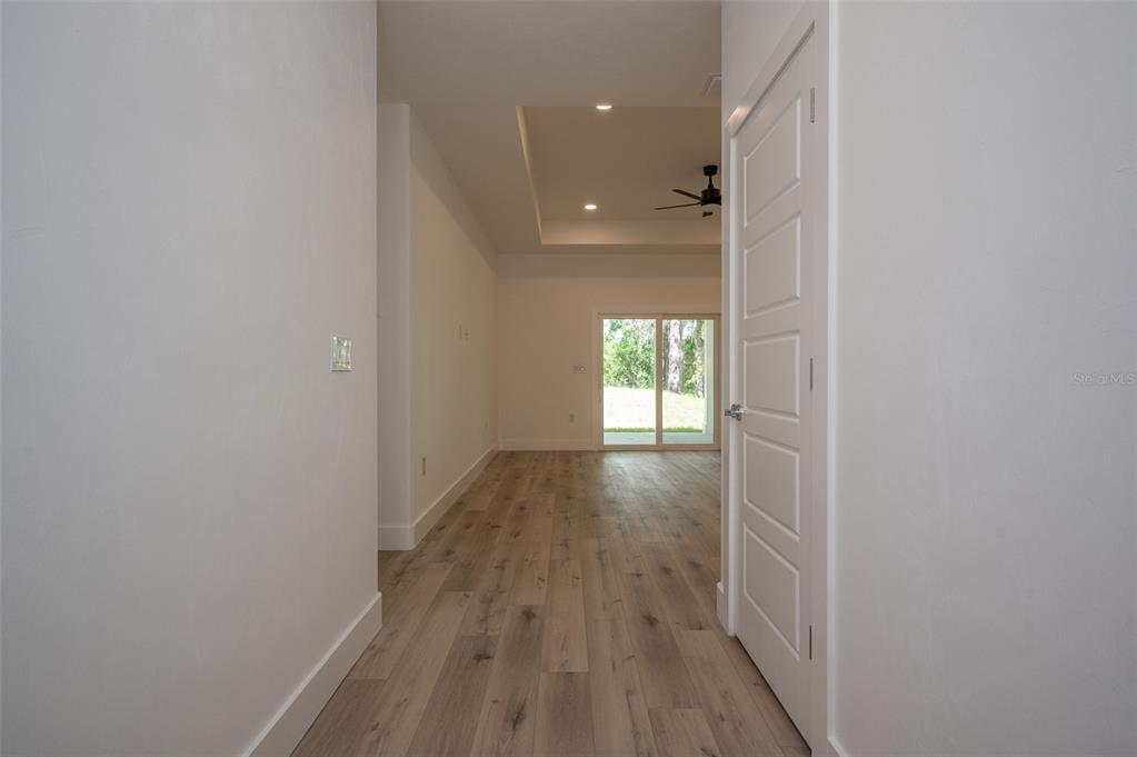 A hallway with wood-look flooring leads to a living area with a tray ceiling — 832 NW 5TH STREET, MICANOPY, FL