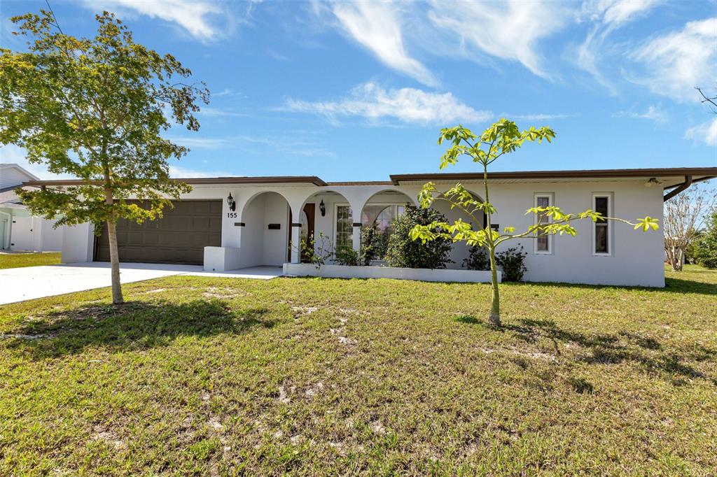 A single-story house with a white facade, arched entryway, and a brown garage door — 155 MORGAN LANE SE, PORT CHARLOTTE, FL
