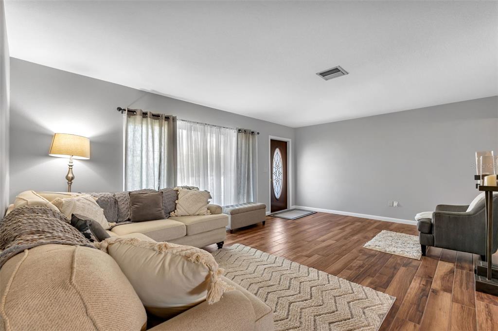 A living room features light gray walls, wood-look tile flooring, and a front entry door — 155 MORGAN LANE SE, PORT CHARLOTTE, FL