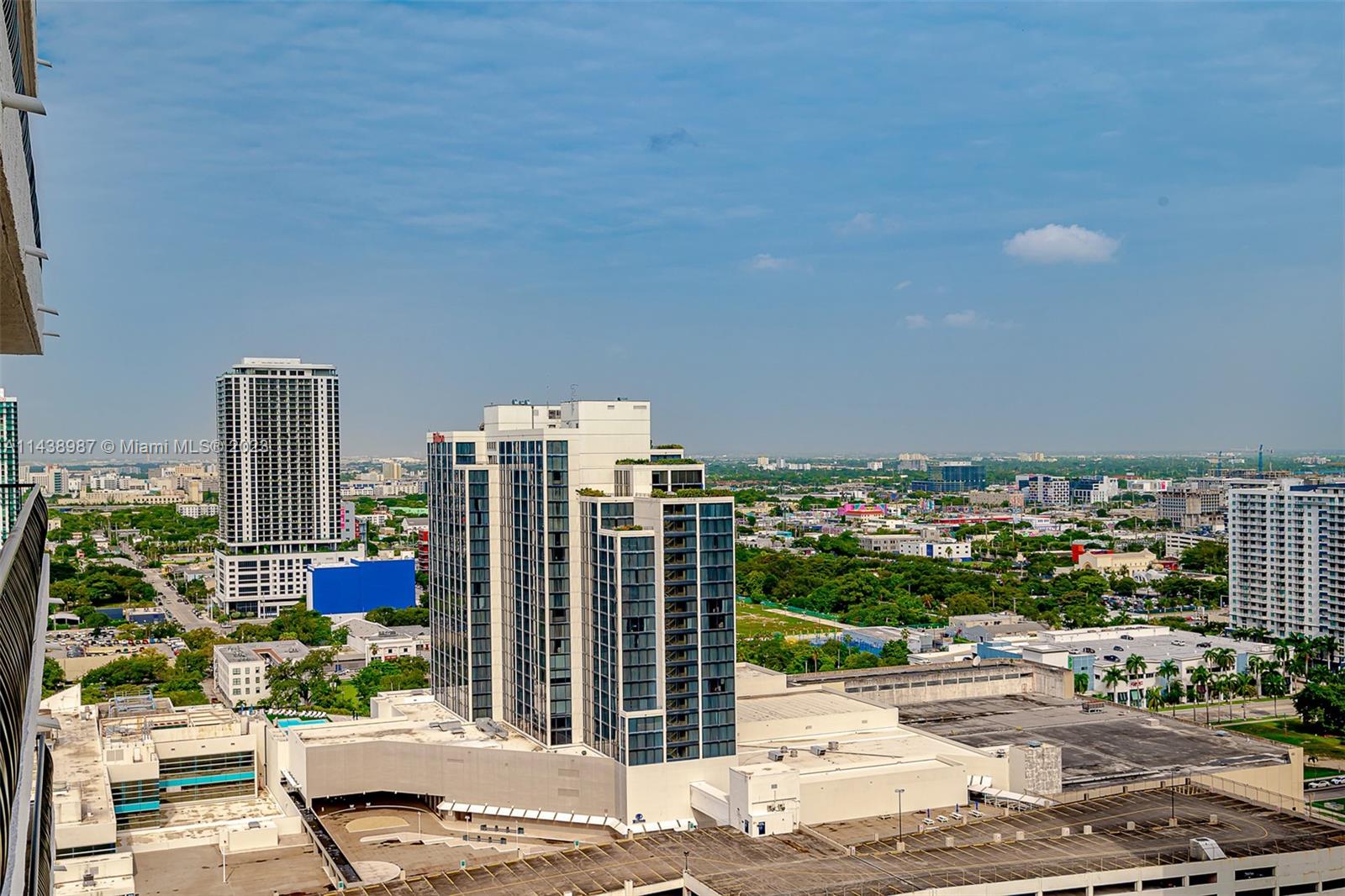 An elevated view shows a city skyline with tall residential buildings and a parking structure — 555 NE 15th St # 32E, Miami FL 33132, MIAMI, FL