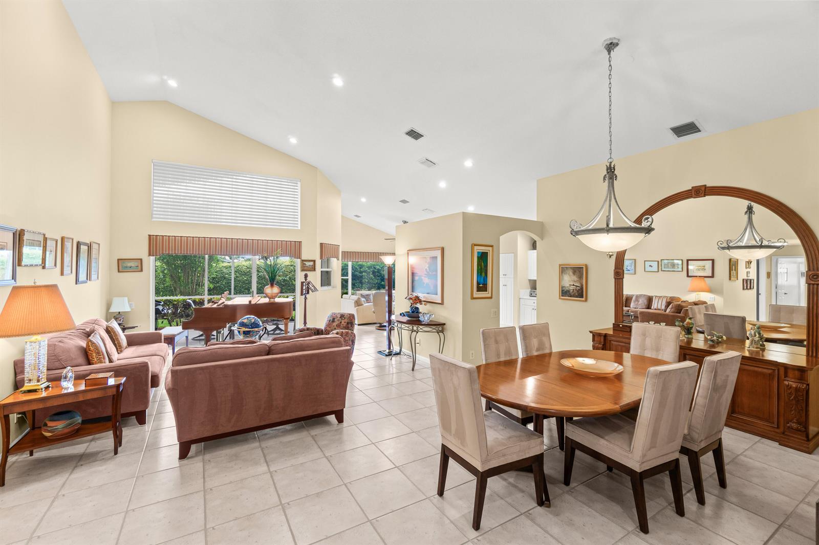 An open-concept living and dining area features vaulted ceilings, tile flooring, and a grand piano — 6952 Grenelefe Road, Boynton Beach FL 33437, BOYNTON BEACH, FL