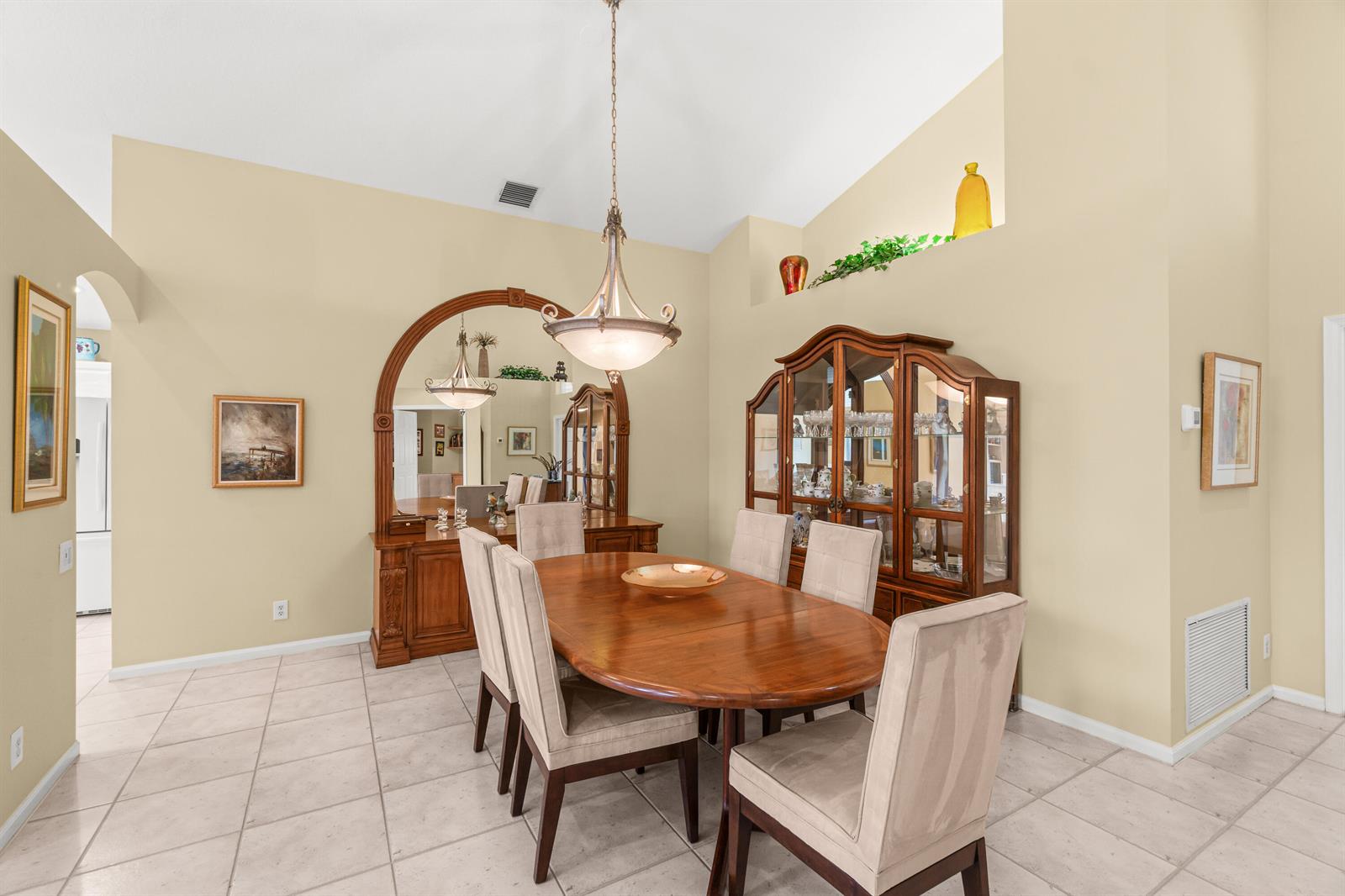 A dining room features a wooden table, upholstered chairs, a hutch, and a large mirror — 6952 Grenelefe Road, Boynton Beach FL 33437, BOYNTON BEACH, FL