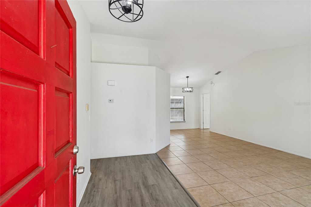 An entryway with a red door leads into a living area with tiled floors — 11903 STEPPINGSTONE BOULEVARD, TAMPA, FL