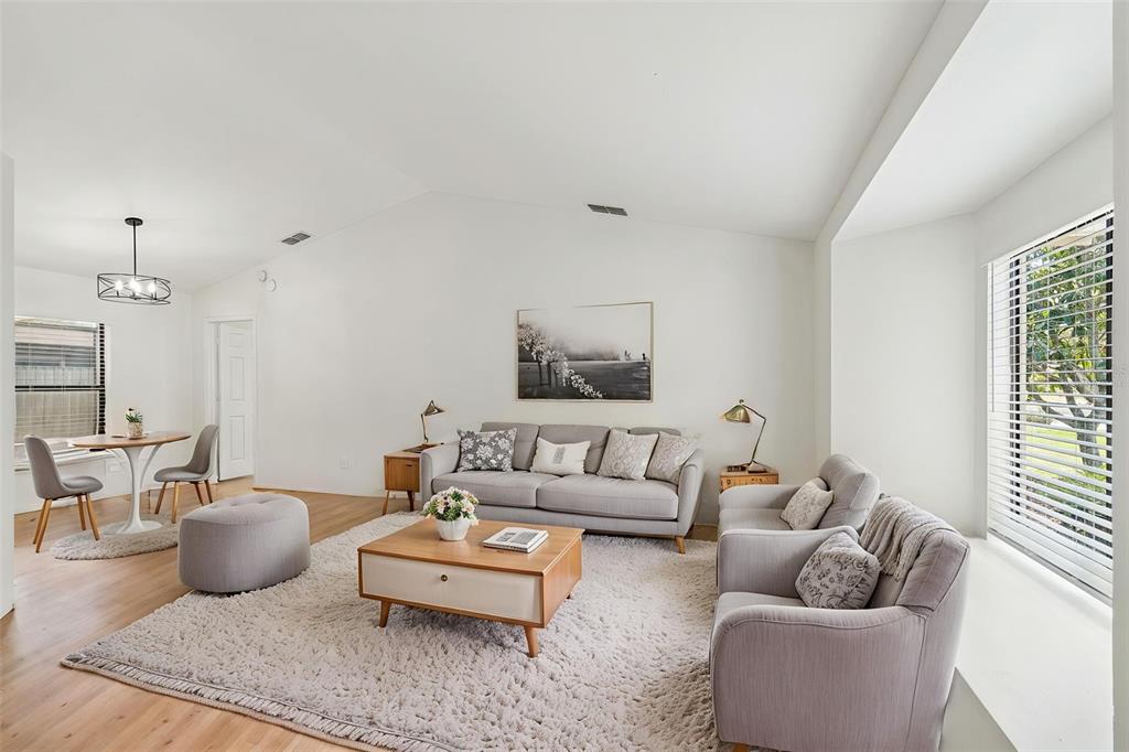 A living room features light wood flooring, a gray sofa set, and a dining area — 11903 STEPPINGSTONE BOULEVARD, TAMPA, FL