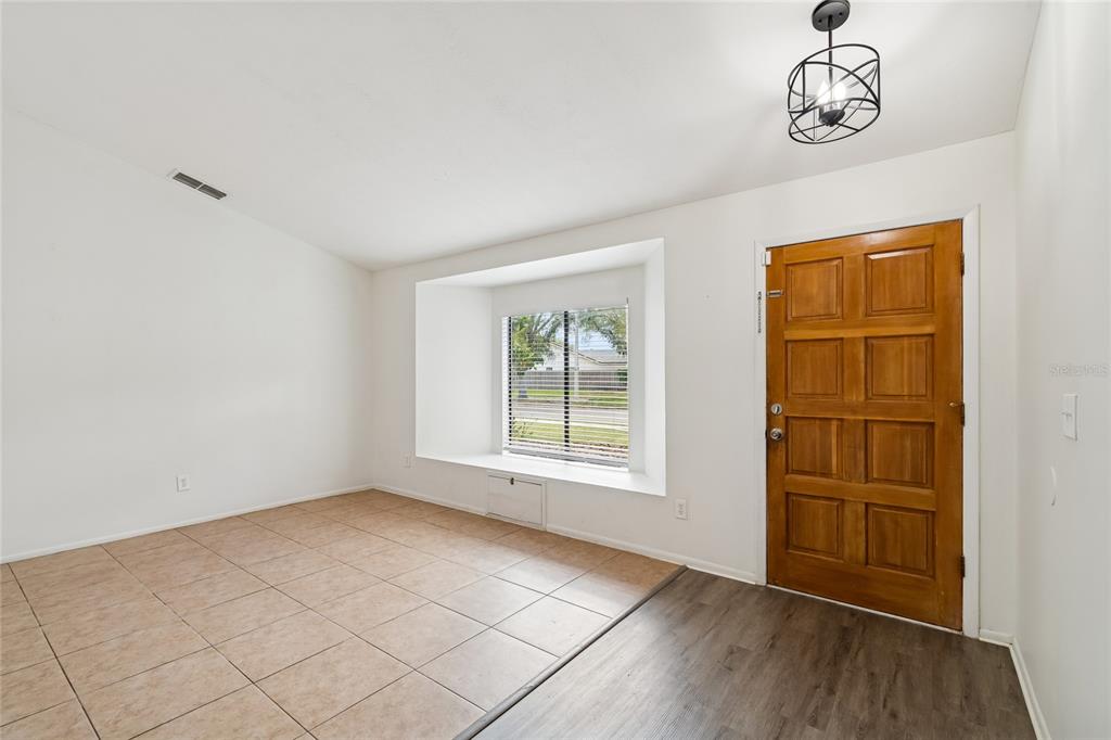 An entryway features a wood front door, tile flooring, and a window with a seat — 11903 STEPPINGSTONE BOULEVARD, TAMPA, FL