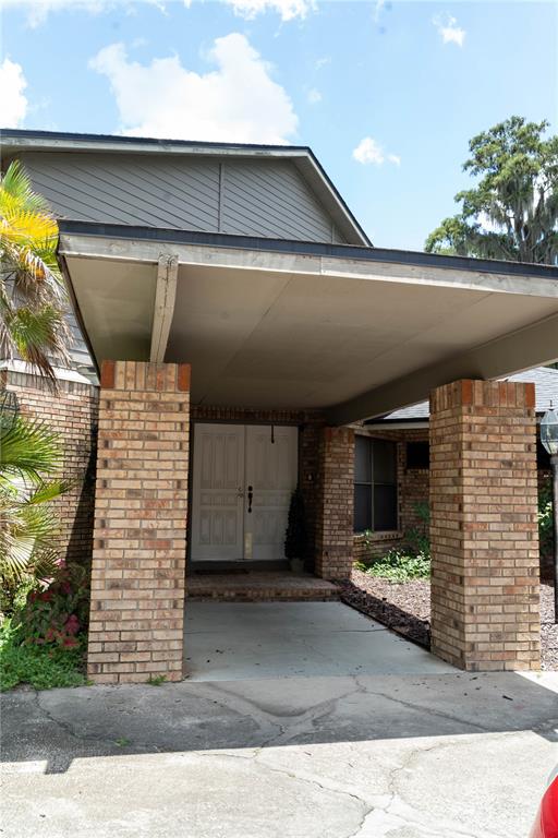 A brick-columned covered entryway leads to a double-door front entrance of a residential home — 4365 REAL COURT, ORLANDO, FL