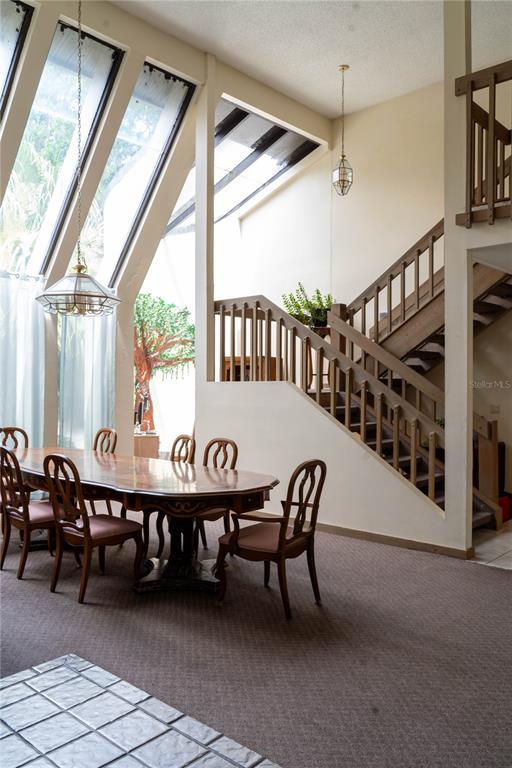 A dining room with a wooden table, chairs, and a staircase under a sloped ceiling — 4365 REAL COURT, ORLANDO, FL