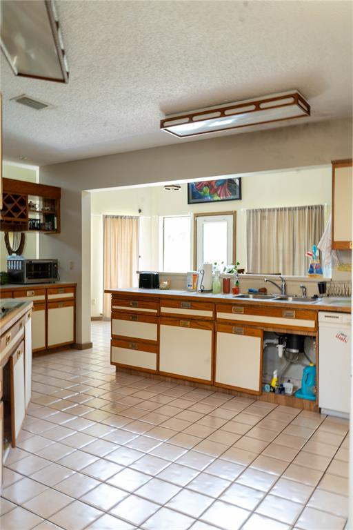 A kitchen features light-colored tile flooring, wood-trimmed cabinets, and an open view into another room — 4365 REAL COURT, ORLANDO, FL