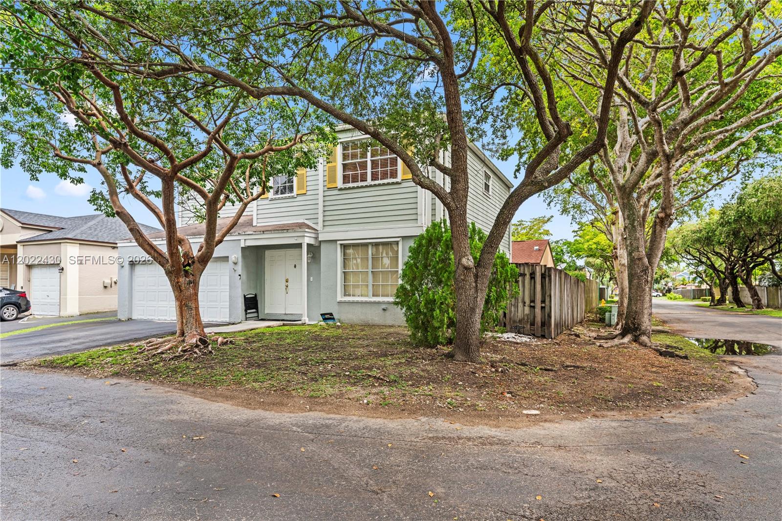A two-story house with light-colored siding, a garage, and large trees in the front yard — 22316 SW 99th Ave, Cutler Bay FL 33190, CUTLER BAY, FL