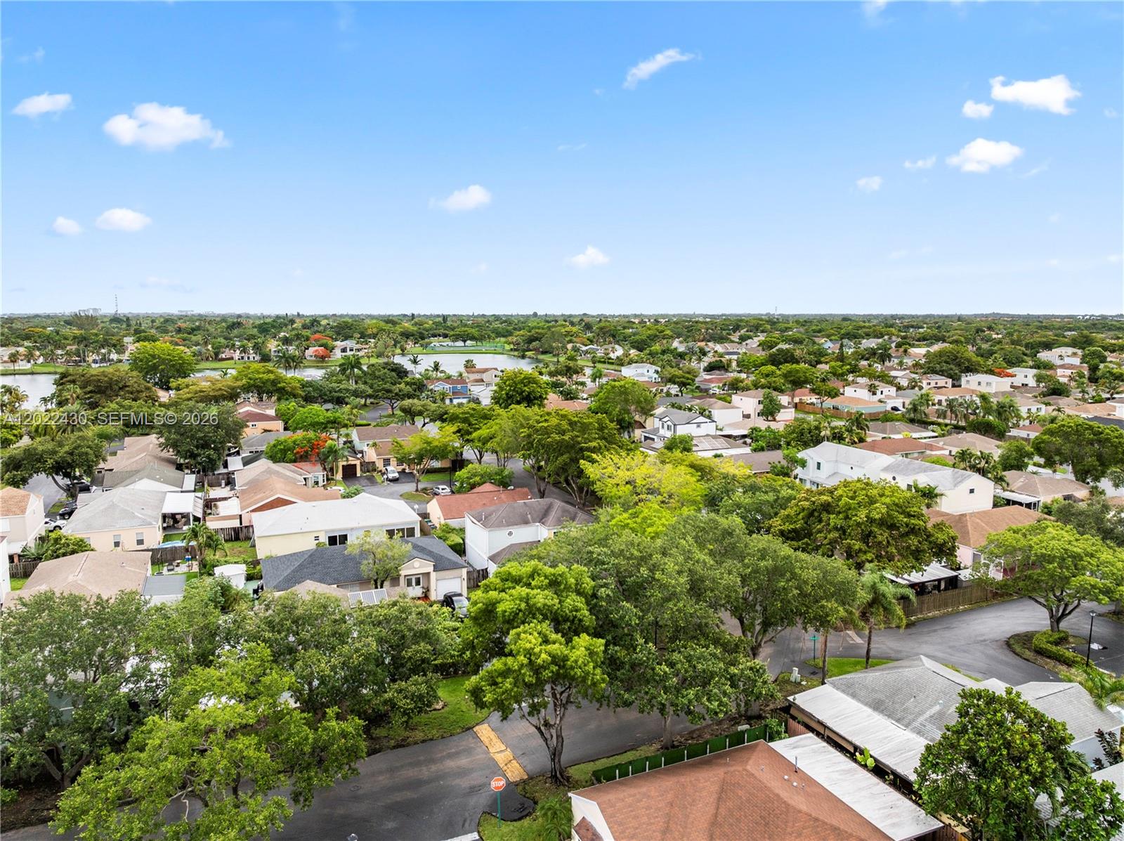 An aerial view shows a suburban neighborhood with many trees, houses, and a lake — 22316 SW 99th Ave, Cutler Bay FL 33190, CUTLER BAY, FL