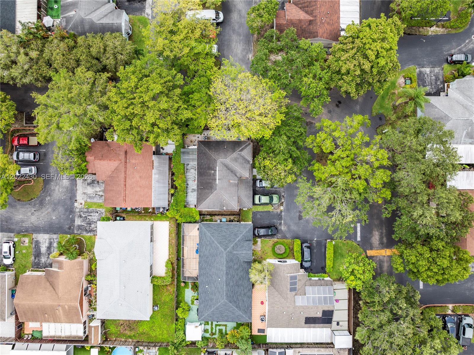 An aerial view shows several residential houses surrounded by trees, parking areas, and paved roads — 22316 SW 99th Ave, Cutler Bay FL 33190, CUTLER BAY, FL