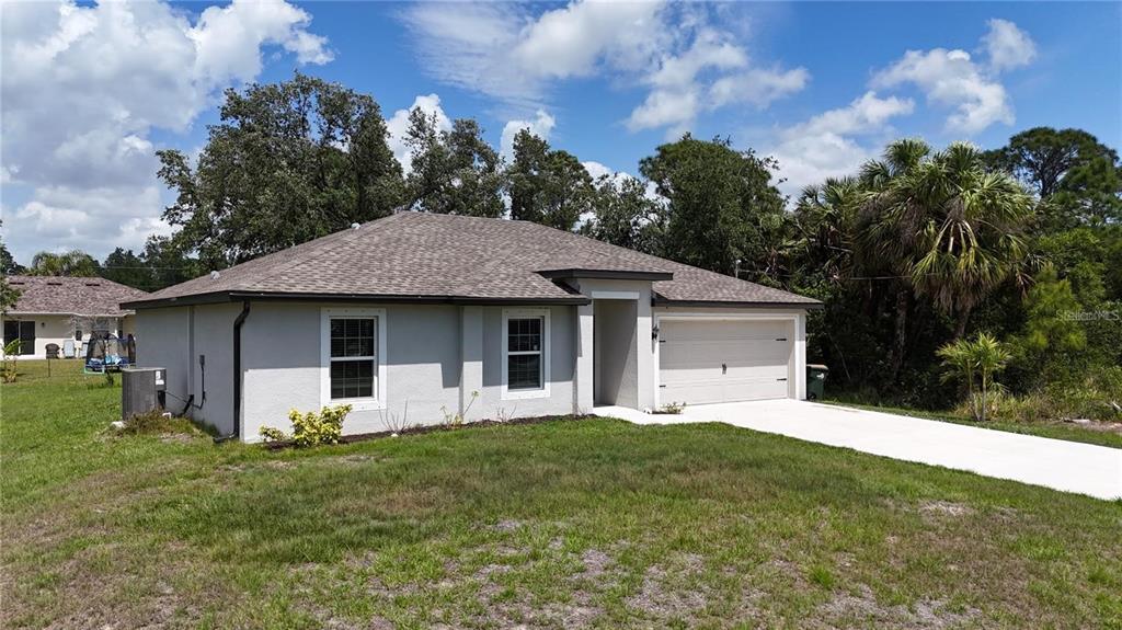 A single-story house with a gray stucco exterior, a shingled roof, and a concrete driveway — 4127 SNOWDROP STREET, NORTH PORT, FL