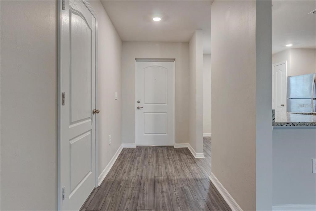 An entryway with gray wood-look flooring, a white front door, and a side door — 4127 SNOWDROP STREET, NORTH PORT, FL