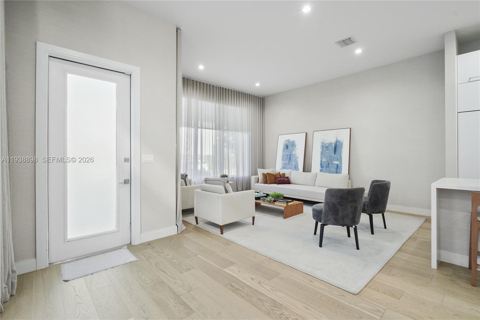 A modern living room features light wood floors, a white sofa, and two gray chairs — 8144 NW 43rd St, Doral FL 33166, DORAL, FL