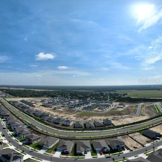 An aerial view shows a suburban neighborhood with new houses and undeveloped land — 5161 GREEN BELT DRIVE, HAINES CITY, FL
