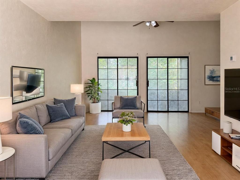 A living room features a grey sofa, wood coffee table, and black-framed sliding glass doors — 900 SW 62ND BOULEVARD UNIT G41, GAINESVILLE, FL