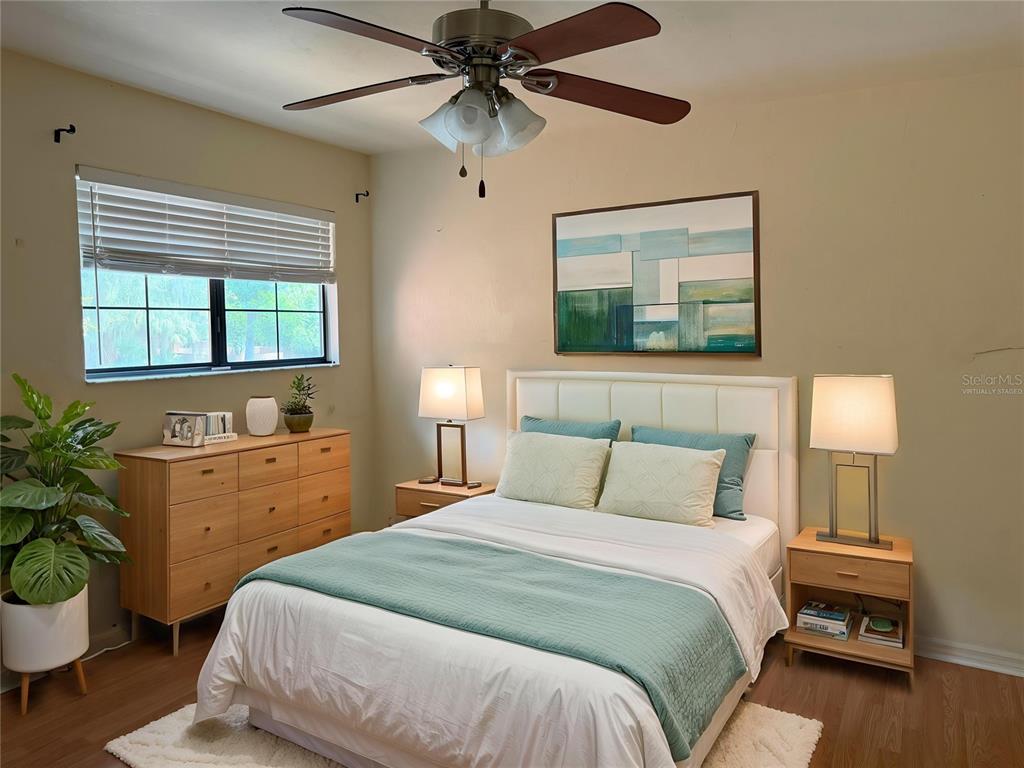 A bedroom features a bed with teal bedding, two nightstands, a dresser, and a ceiling fan — 900 SW 62ND BOULEVARD UNIT G41, GAINESVILLE, FL
