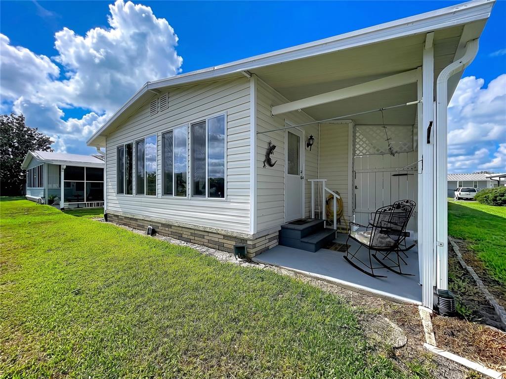 A grassy backyard slopes down toward a lake with trees under a blue sky — 2055 S FLORAL AVENUE UNIT 192, BARTOW, FL