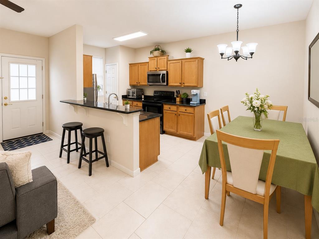 A kitchen with wood cabinets, black countertops, and a dining area with a green tablecloth — 66 MOULTRIE VILLAGE LANE, ST AUGUSTINE, FL