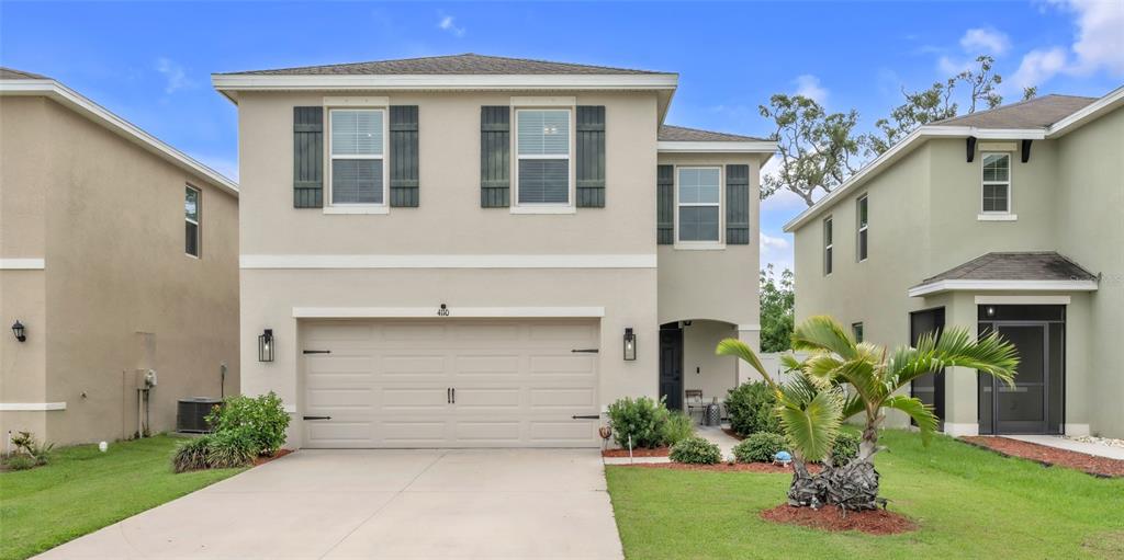A two-story suburban house features a beige stucco exterior, a two-car garage, and shutters — 4110 WILLOW HAMMOCK DR, PALMETTO, FL