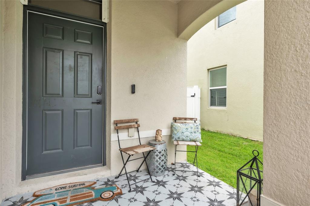 A covered front porch features a dark door, patterned tile flooring, and two metal chairs — 4110 WILLOW HAMMOCK DR, PALMETTO, FL