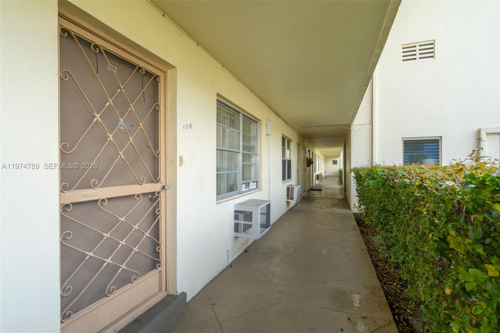 An exterior walkway leads past a door numbered 106 with a decorative metal security gate — 17050 NE 14th Ave # 106, Miami FL 33162, MIAMI, FL