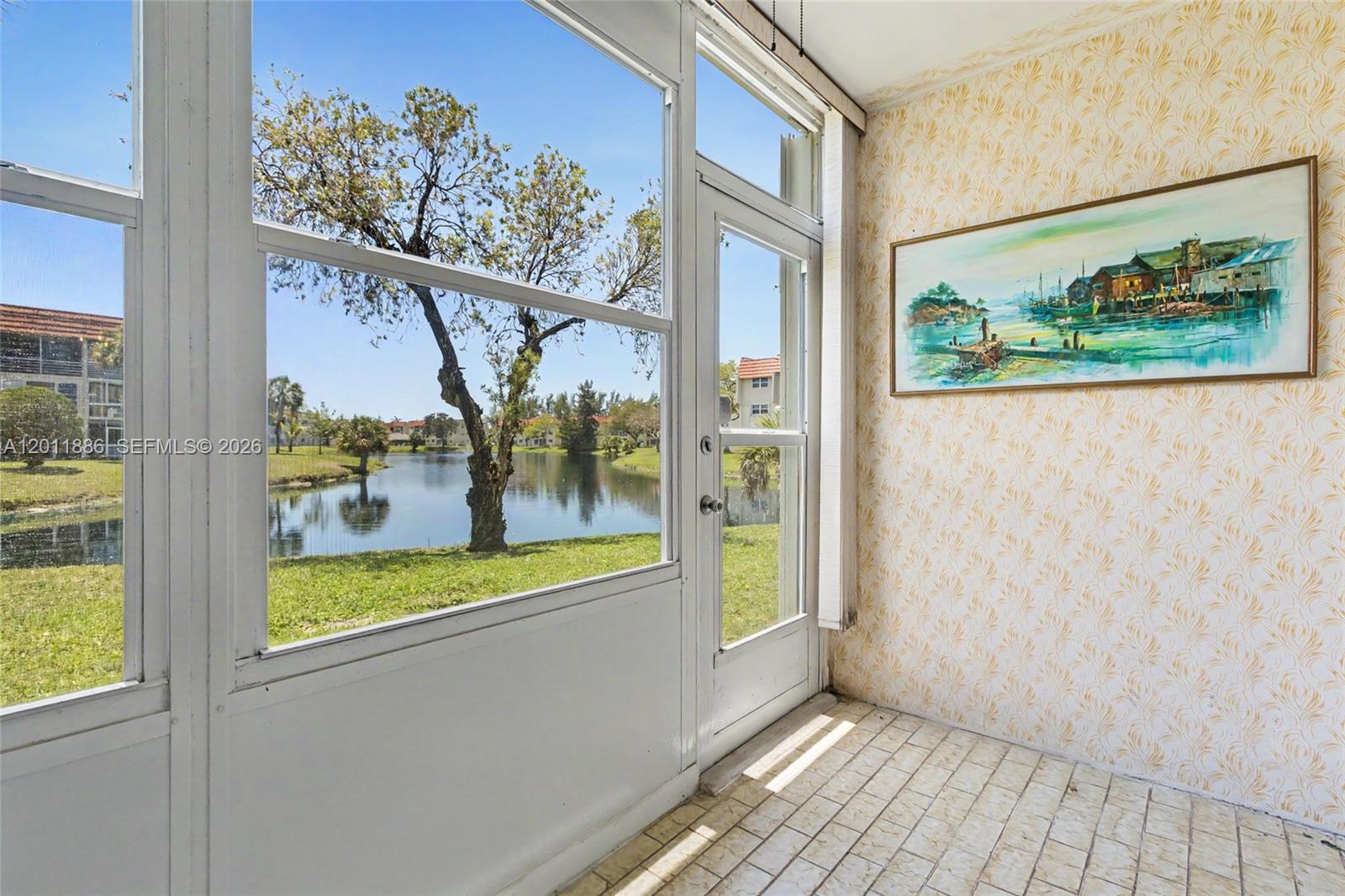 A living room features tiled floors, a ceiling fan, a chandelier, and a sliding glass door — 2831 E Sunrise Lakes Dr # 105, Sunrise FL 33322, SUNRISE, FL