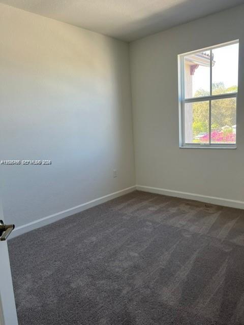 An empty bedroom features beige walls, gray carpeting, and a single window — 12663 NW 24th Ave, Miami FL 33167, MIAMI, FL